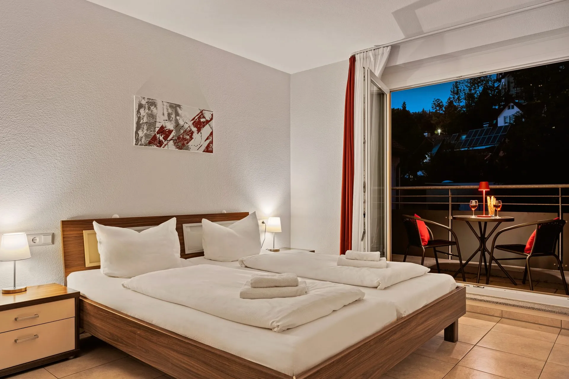 Schlafzimmer in der blauen Stunde, dahinter der beleuchtete Balkon