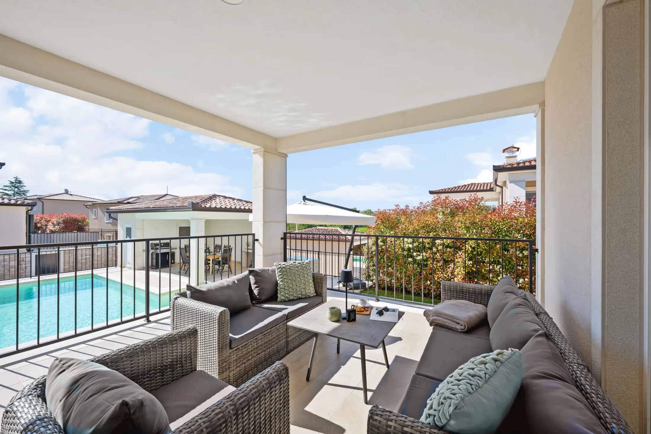 Covered terrace with lounge furniture and a view of the pool