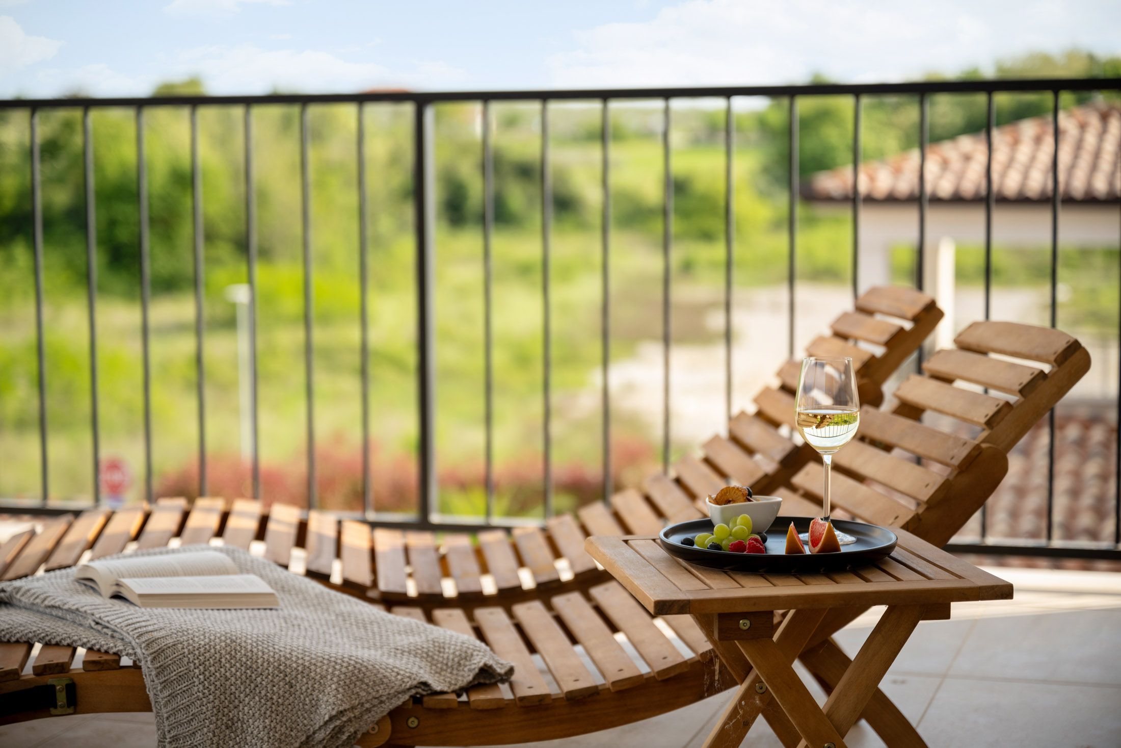 Balcony lounger with a wine glass, plate of fruit and a book