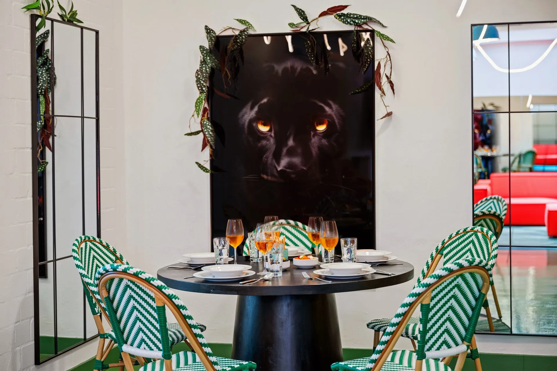 Runder Esstisch mit gemusterten Stühlen vor einem großformatigen Panther-Bild
