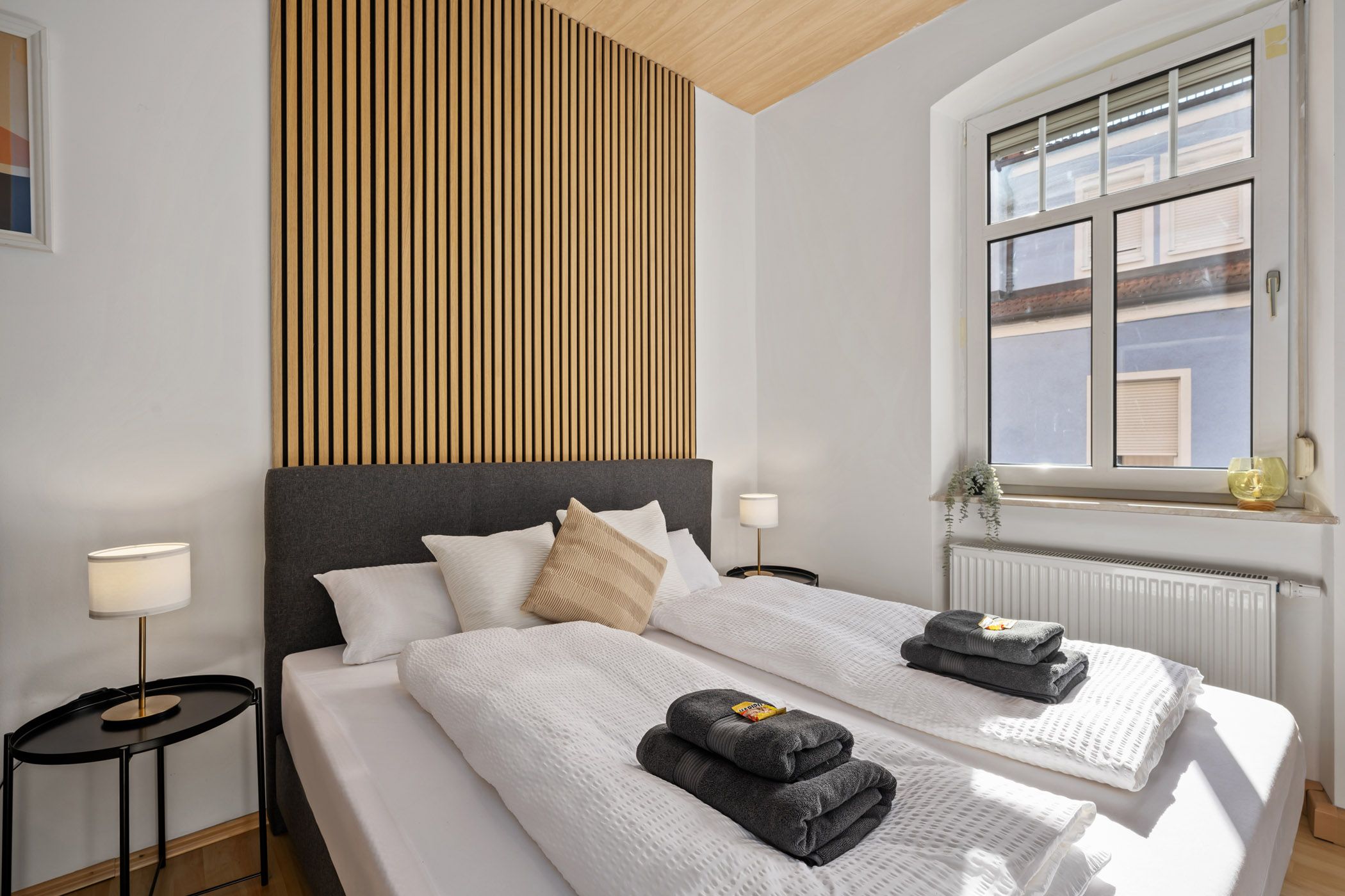 Bedroom with a wooden slatted wall and bedside lamps