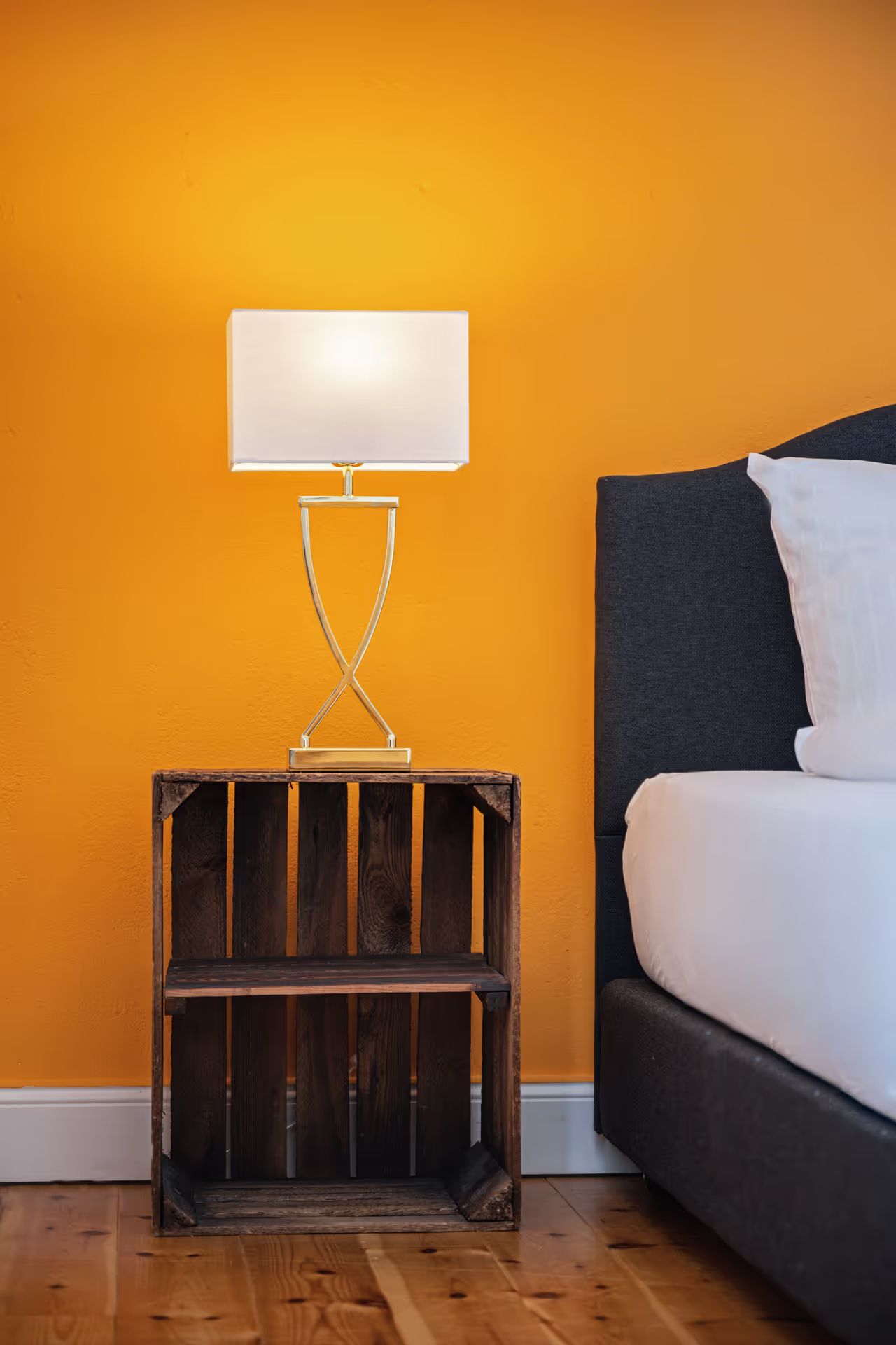 Nightstand with a lamp against an orange wall