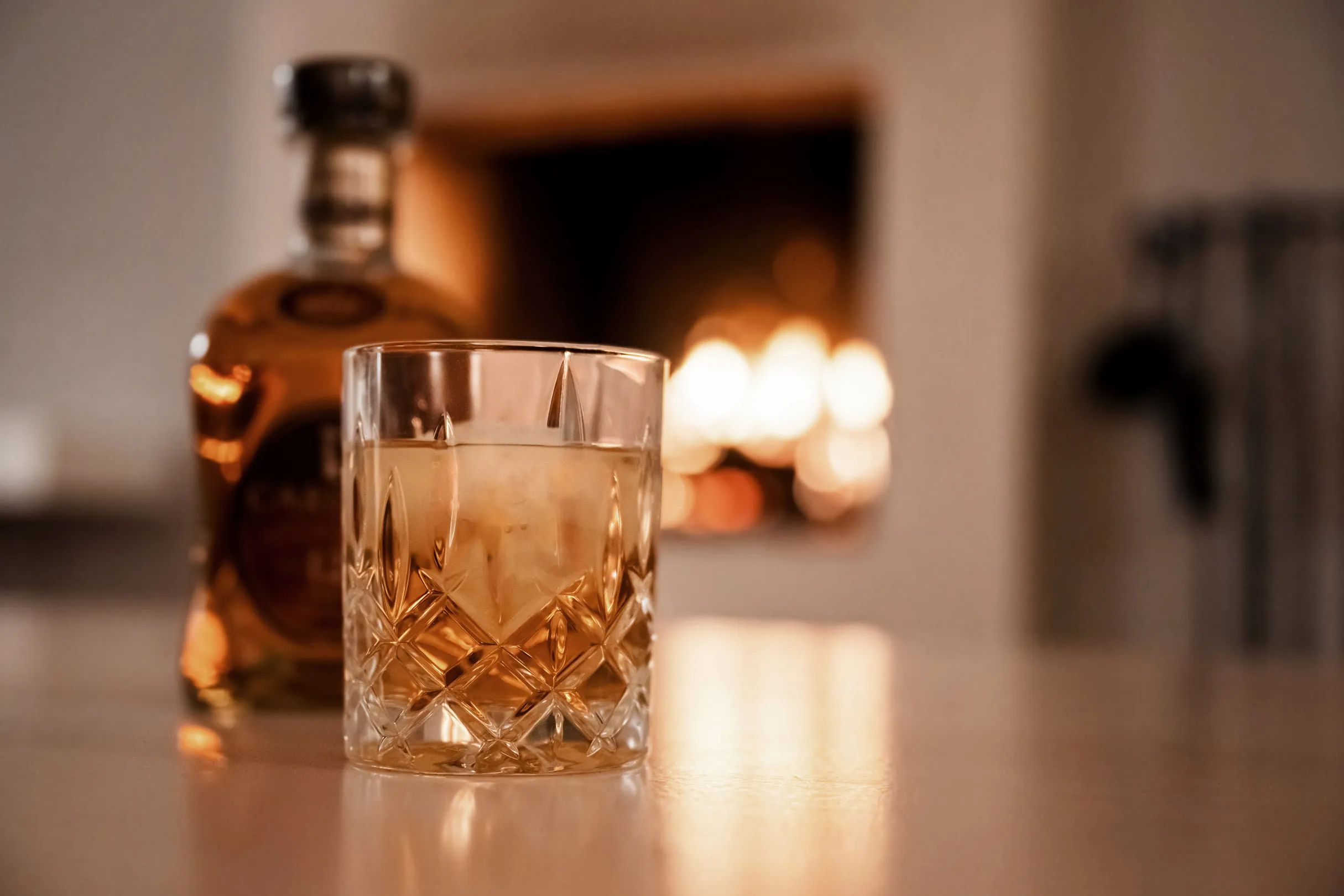 Glass of whisky on the table in front of the fireplace