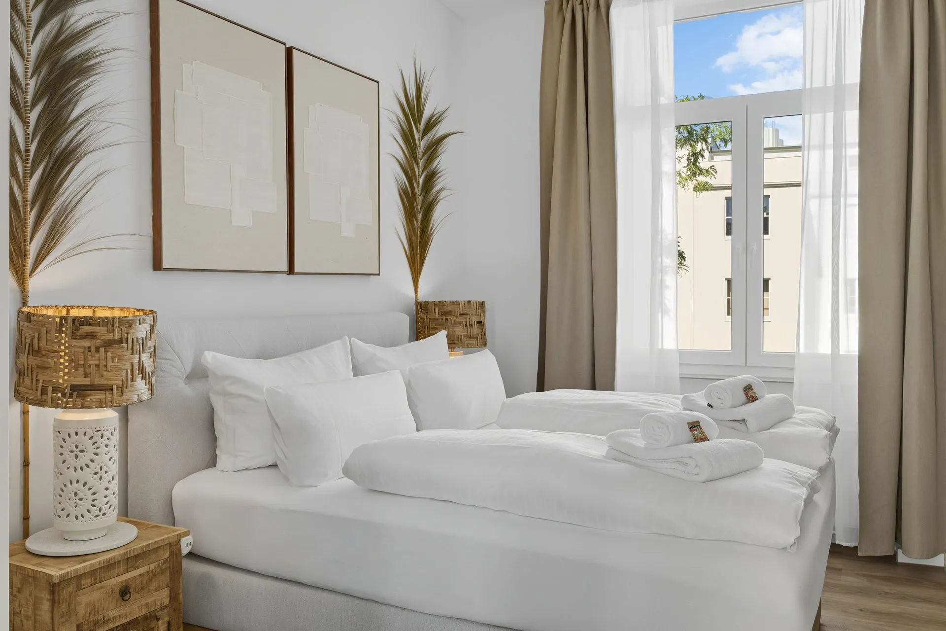 Helles Schlafzimmer mit weißer Bettwäsche und geflochtener Tischleuchte