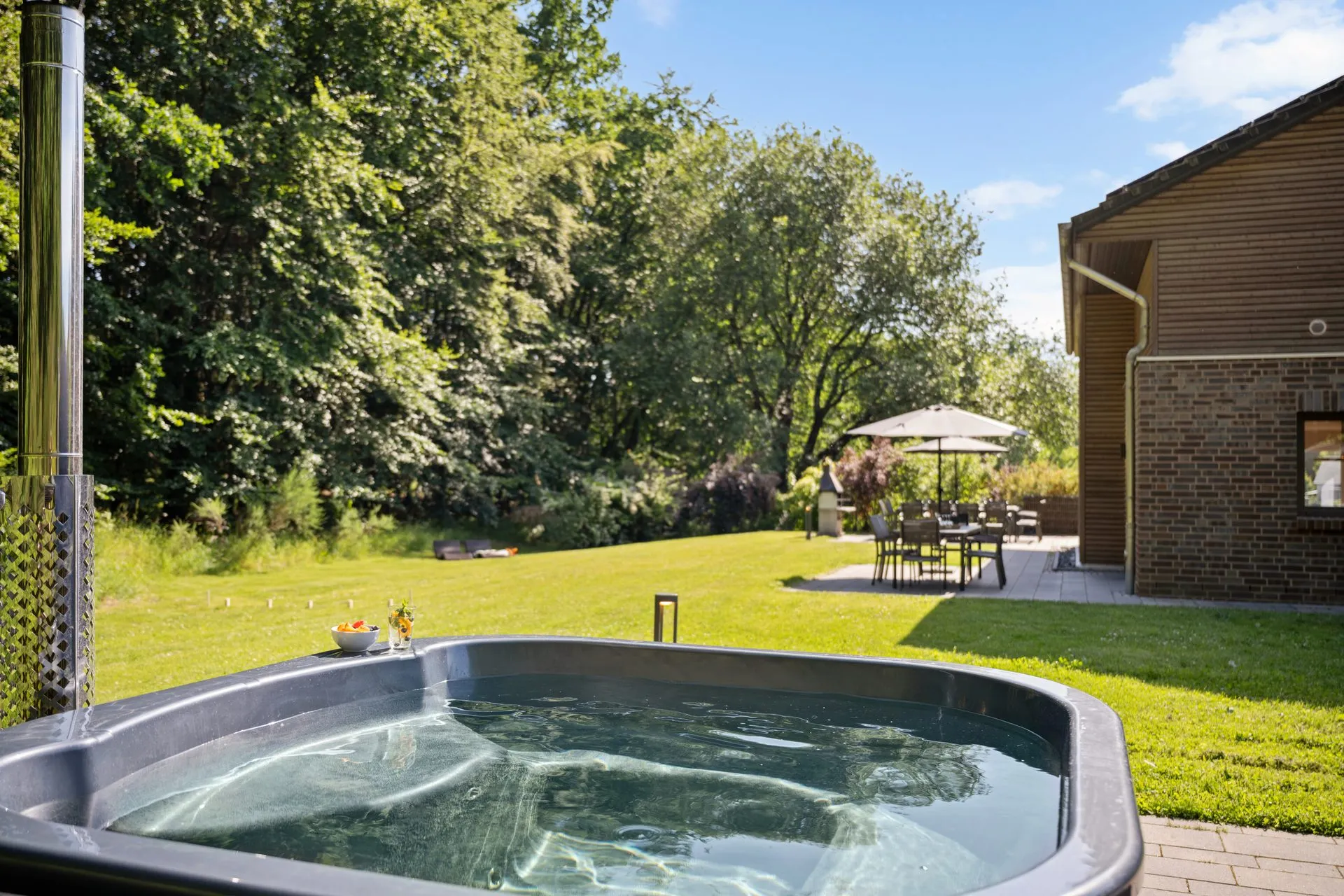 Sprudelnder Außen-Whirlpool auf der Rasenfläche neben dem Haus