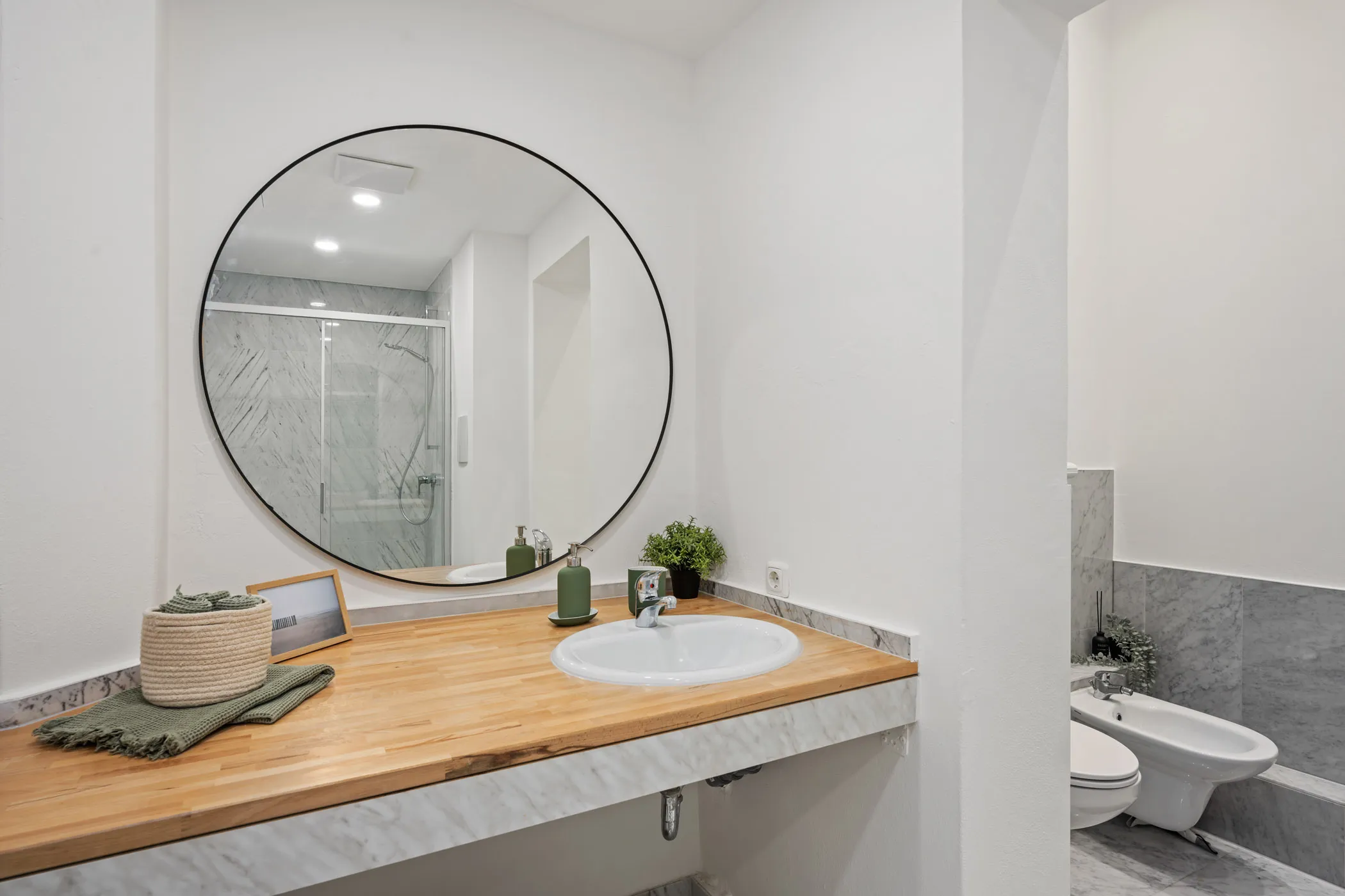 Modern bathroom with a round mirror and wooden washstand
