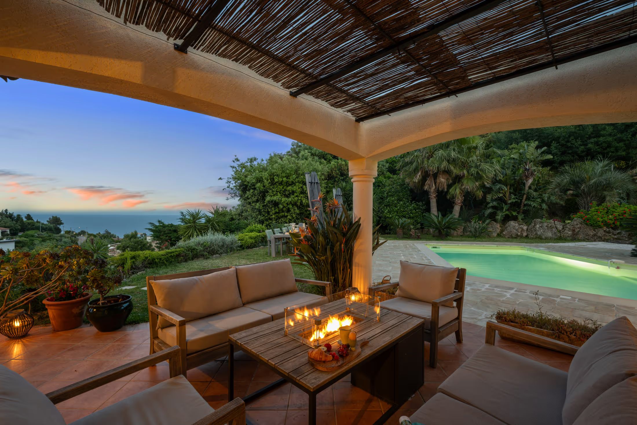 Lounge area with a fire pit and sea view in the evening