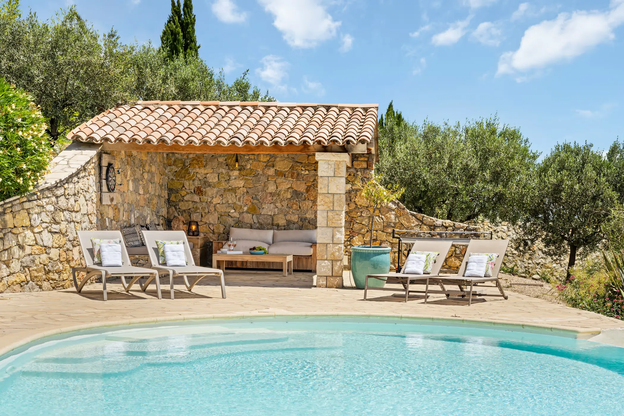 Pool house with loungers at Villa La Genestière in France, surrounded by olive trees