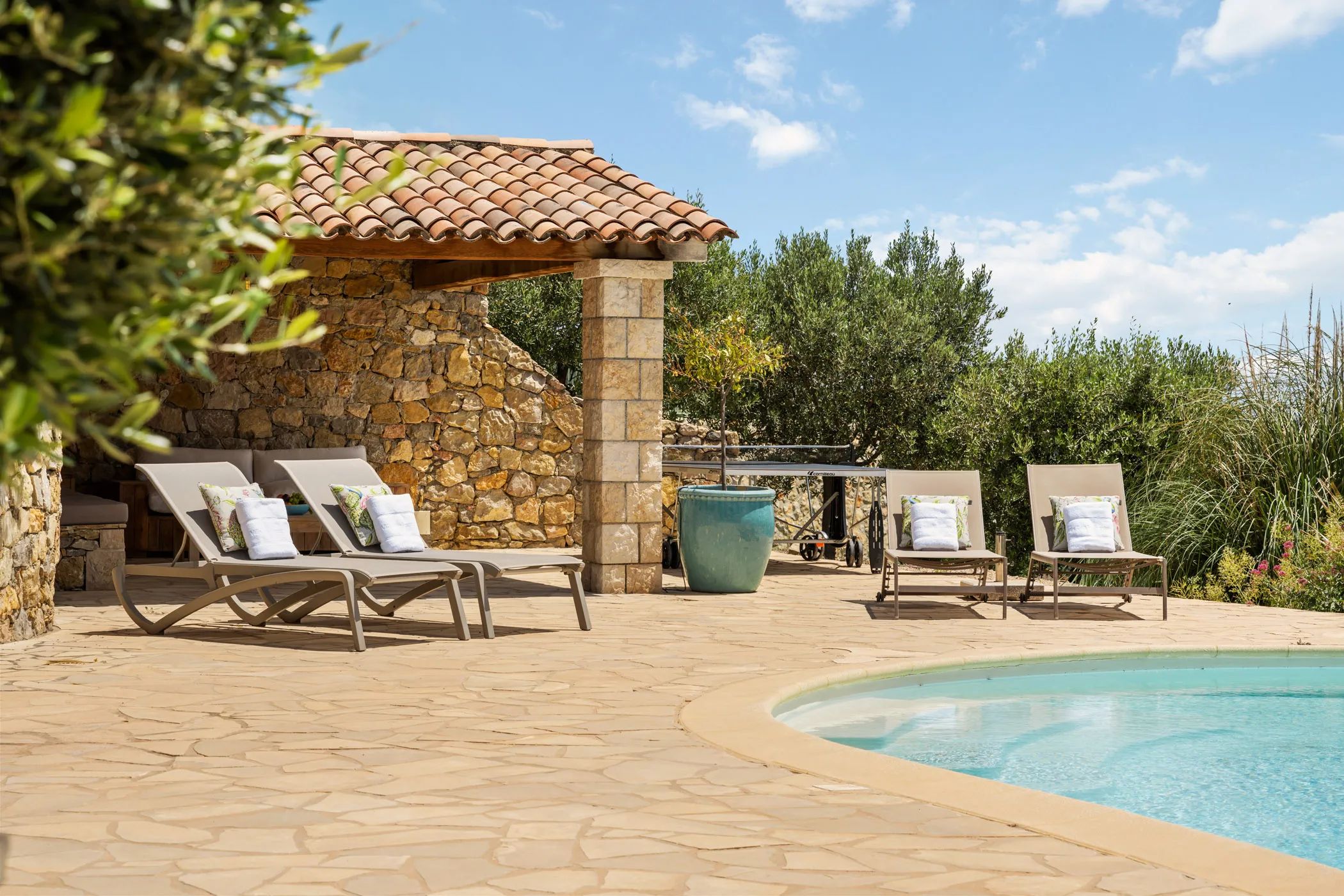 Pool terrace with loungers in front of a natural stone pavilion