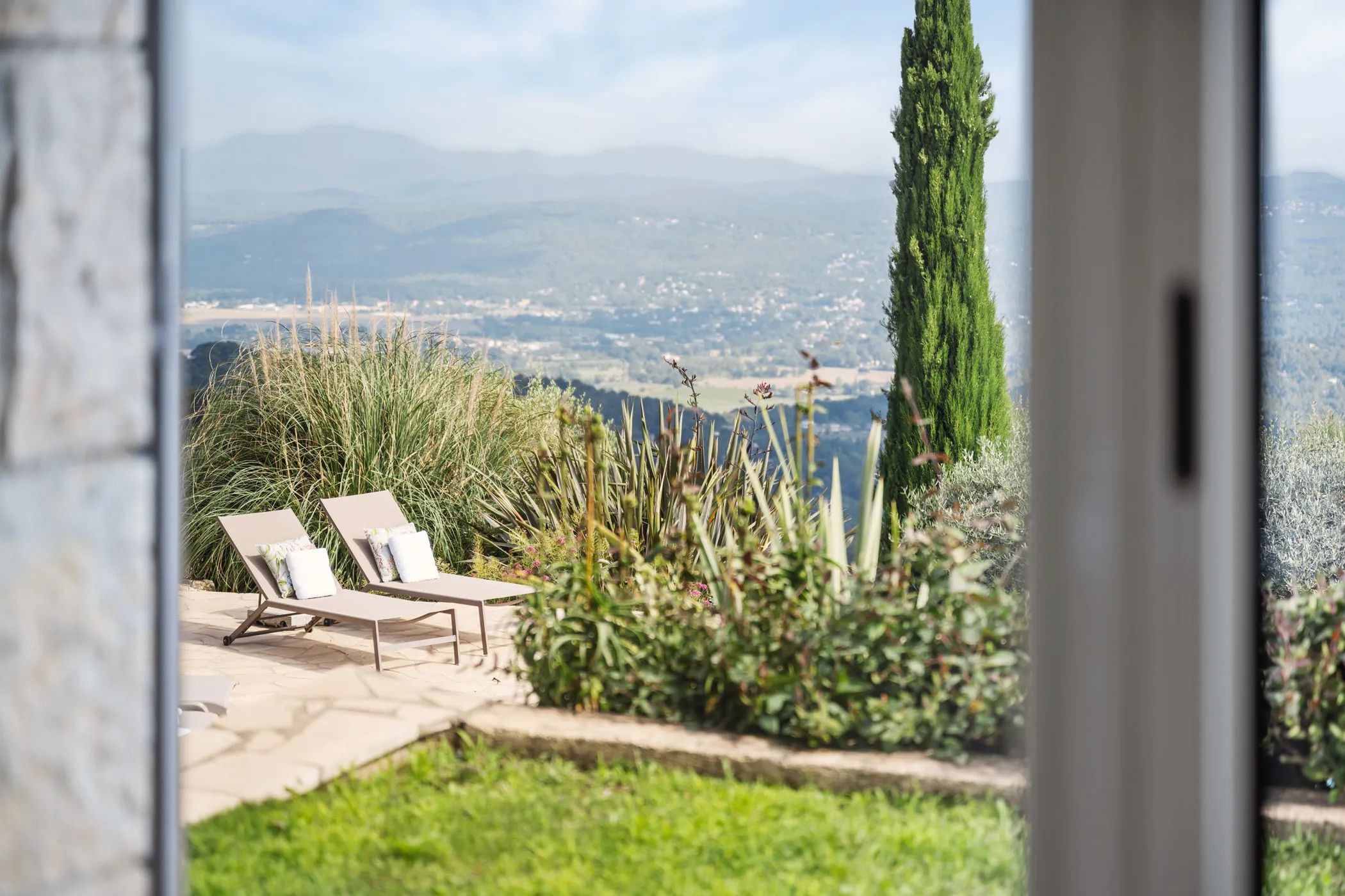 Garden view through the window onto loungers and the valley