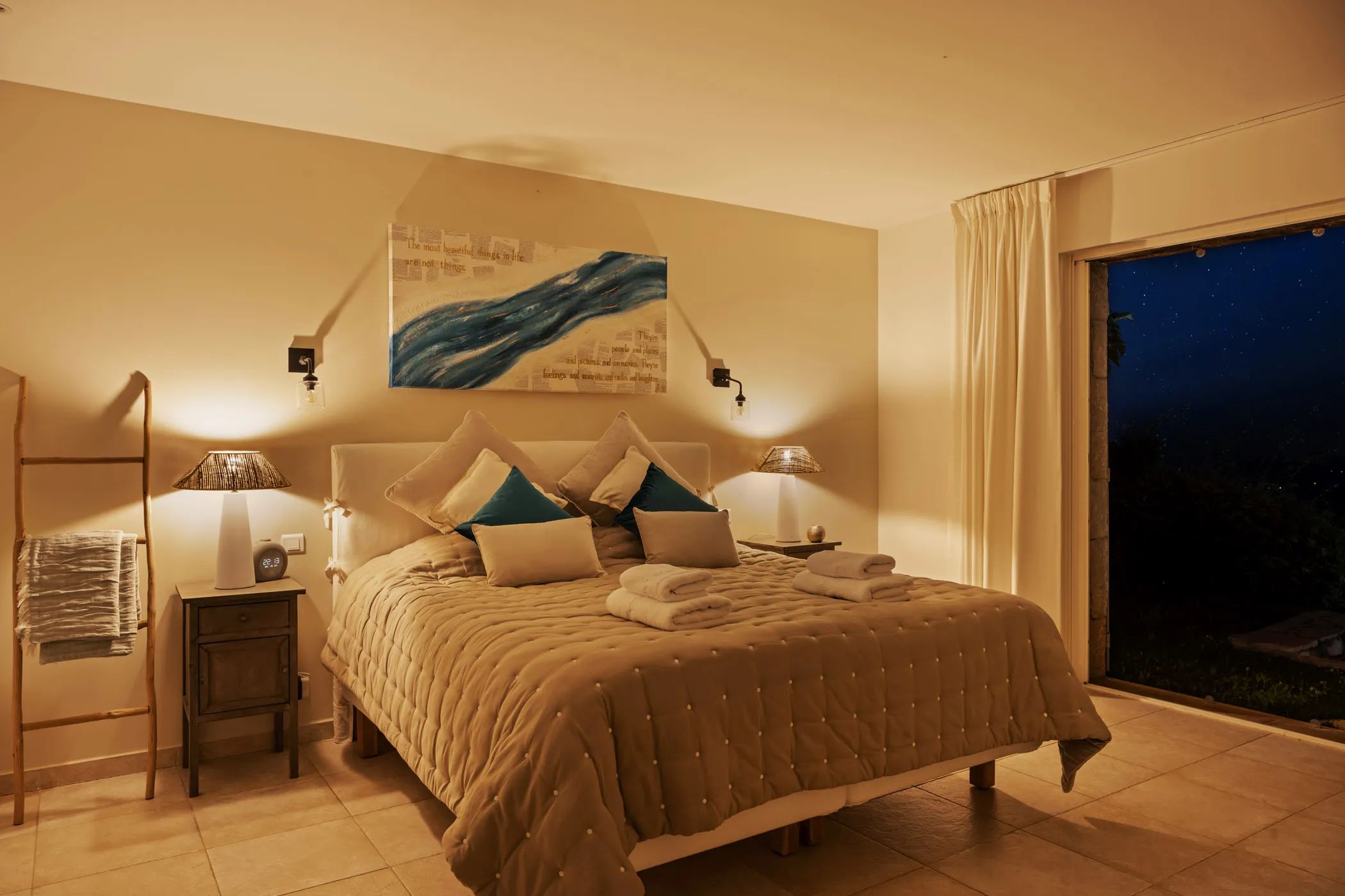 Bedroom with a double bed, warm lamplight, and a nighttime view through the window