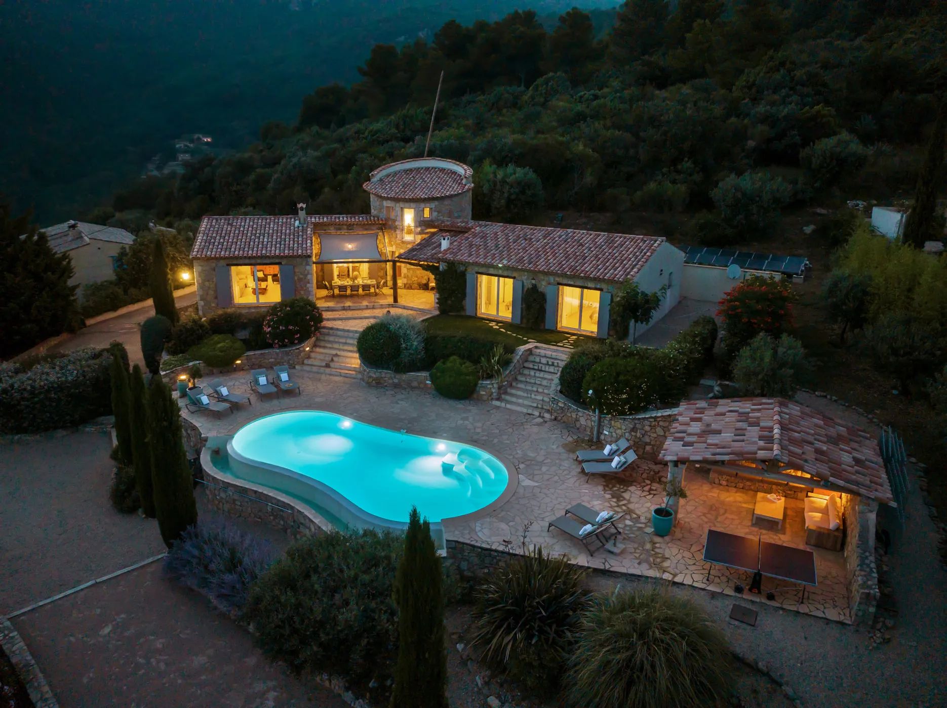 Aerial shot of the villa with an illuminated pool at night